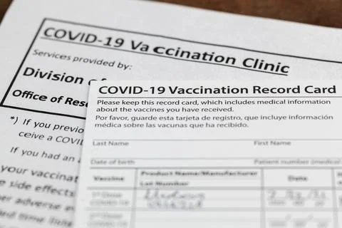 Close up isolated image of a COVID 19 vaccination record card on a wooden des Stock-Fotos