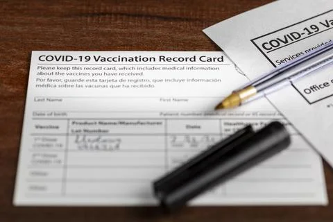 Close up isolated image of a COVID 19 vaccination record card on a wooden des Stock-Fotos