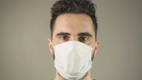 Close-up of Isolated man with surgical Mask, brown hair and eyes, facing at 動画素材 129867735