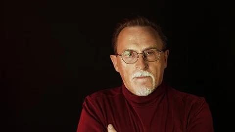Close up isolated portrait of senior man in glasses on black background Stock Footage 129183177