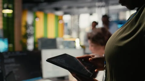 Close up of IT professional in startup office working on tablet with AI Stock Footage 323332314
