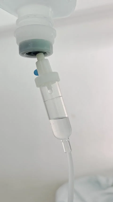 Close Up IV Drip Normal Saline Flow in Hospital Medical Treatment Setting Stock Footage 329677743