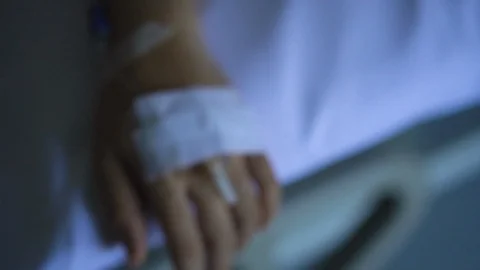 Close up IV drip solution in a patient's hand while lying on bed in hospital. Video stock 103189905