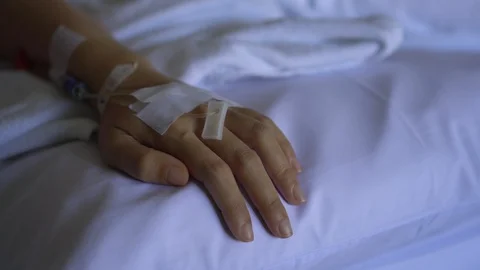 Close up IV drip solution in a patient's hand while lying on bed in hospital. Video stock 103193514