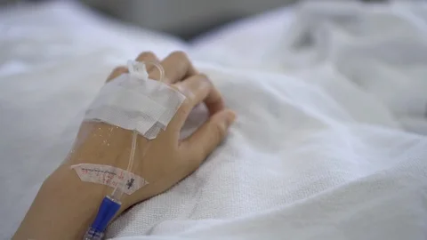 Close up IV drip solution in a patient's hand while lying on bed in hospital. Stock-Footage 103195788