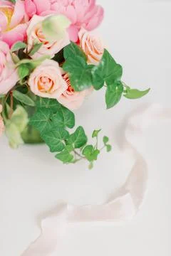 Close up of ivy and peach flowers with pale pink ribbon Stock Photos