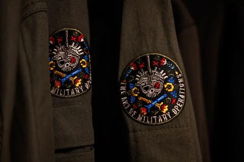 Close-up of a jacket with an embroidered tactical patch displaying military.. Stock Photos