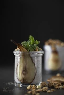 Close up of jar chia seed pudding decorated with slice of dried pear, granola Stock Photos