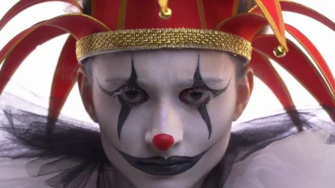 Close up of the jester with makeup and a red hat with little bells, twitching Stock Footage 104544660