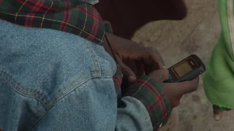 Close-up of jkid cket using basic mobile phone in rural outdoor setting in Ghana 스톡 동영상 324768601