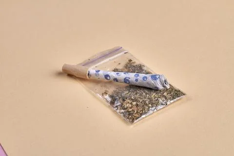 Close-up joint and packet of weed isolated on beige background. Marijuana Fotos de archivo