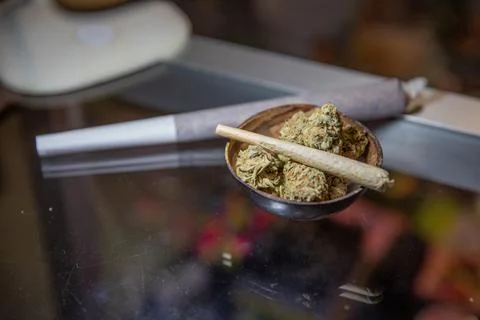 Close up of a joint rolled with marijuana placed on top of raw marijuana Stock Photos