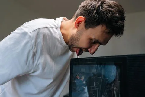 Close-up of joyful computer technician licking a dusty computer case with funny Stock Photos
