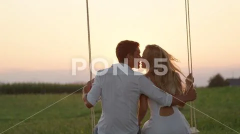 CLOSE UP: Joyous girlfriend and boyfriend kissing on summer evening in nature. Stock Photos