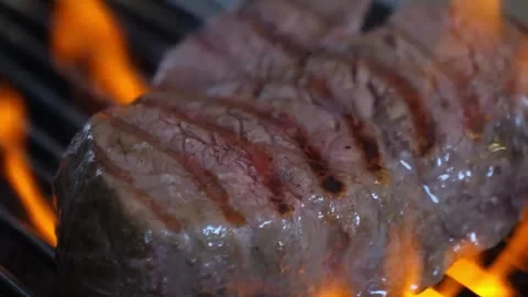 Close-up of Juicy Beef Steak Sizzling on a Hot Grill with Roaring Flames Stock Footage 337677511