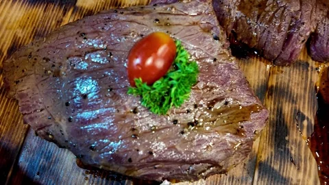 Close Up of Juicy Grilled Beef Steak Garnished with Cherry Tomato Stock Footage 337227343