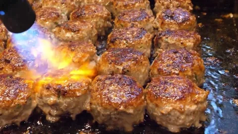 Close Up of Juicy Meatballs Being Seared with Blowtorch on Griddle Video stock 343587247