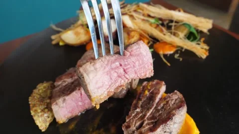 Close-up of Juicy Medium Rare Beef Tenderloin Steak on Fork in Gourmet Restauran Stock Footage 337677613