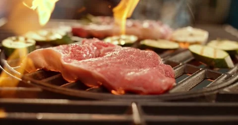 Close up of juicy steak and zucchini slices cooking on grill with flames li.. Stock Footage 337443353