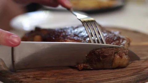 Close-up of a juicy steak being sliced on a wooden cutting board Stock Footage 340563441