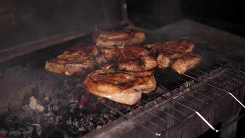 A close-up of a juicy steak is grilled in the evening, a man turns the meat. Stock Footage 294678773