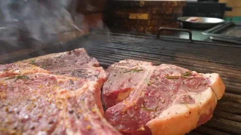 Close-up of Juicy Tomahawk Steaks Sizzling on Outdoor Barbecue Grill with Smoke Видео 338213102