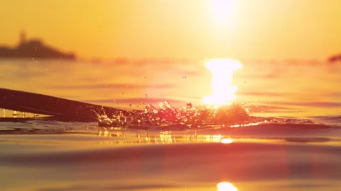 CLOSE UP: Kayaker's paddle splashes ocean water illuminated by the setting sun. Stock Footage 150480891