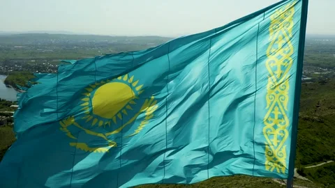 Close up of Kazakh flag flying on wind. Waving flag on flagpole against blue sky Stock Footage 242553474