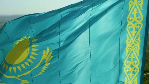 Close up of Kazakh flag flying on wind. Waving flag on flagpole against blue sky Stock Footage 242553981
