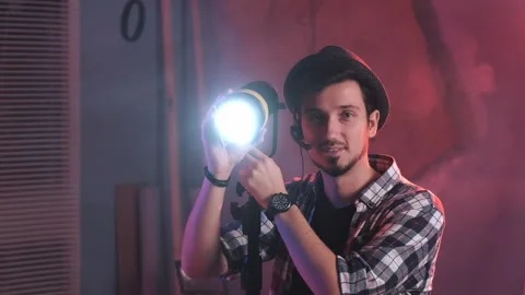 Close-up of key grip turning lamp to the camera and starting smiling. Stock Footage 153470446