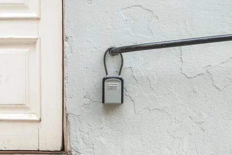 Close up of a key lock box attached to a metal railing next to a residential Stock Photos