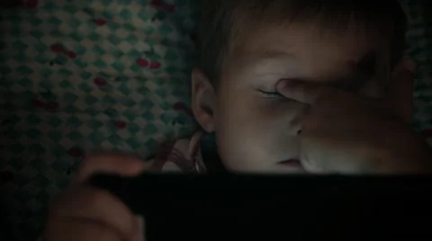 Close-up of kid face looking at tablet computer at night Stock Footage