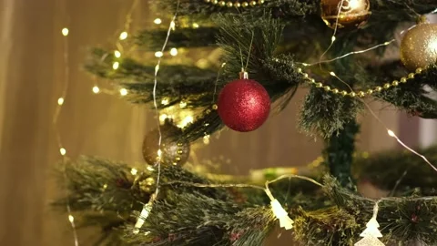 Close up kid hands decorating Christmas tree with balls near festive lights Stock Footage 220174959