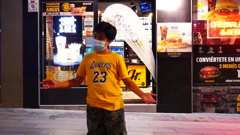 Close Up Kid with Mask in Front of Carls Jr at Night in Madrid Spain 2 Stock Footage 140538489