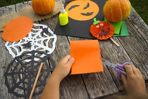 Close up of a kid preparing to make a paper pumpkin craft on a sunny autumn.. Stock Photos