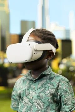 Close up of kid using virtual reality glasses and gadget in city park Stock Photos