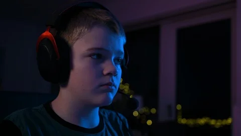 Close up of kid's face while wearing gaming headset and playing video games Stock Footage 100791450