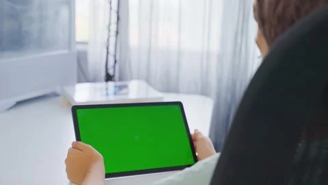 Close up kids hands holding and tapping on a tablet with green screen. Mock up Stock Footage 258366014