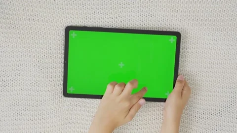 Close up kids hands holding, tapping on a tablet with green screen. Mock up Stock Footage 255480359