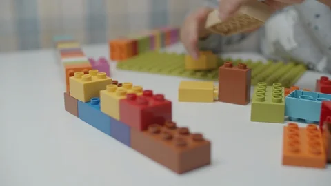 Close up of kids hands playing with constructor on the white table. Building Vídeos de archivo 118823026