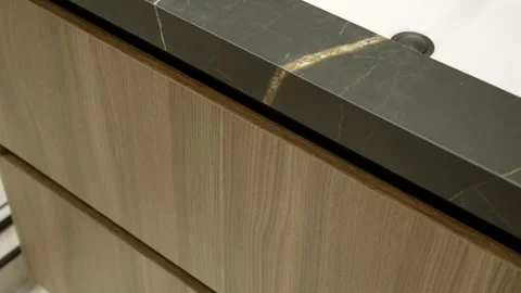 Close up of kitchen cabinets with brown smooth drawers. Black marble frame with Stock Footage 249603316