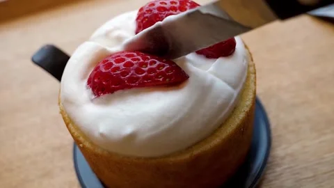 Close-up of a knife cutting into a fresh strawberry chiffon cake topped with whi Stock Footage 331775397