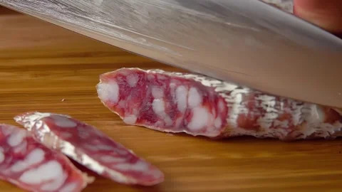 Close-up of a knife cutting off a piece Jerked sausages Stock Footage 293493549