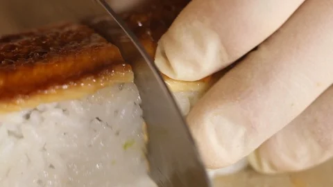 Close-up of knife cutting sushi roll of rice and smoked eel with a knife. Stock Footage 120816168