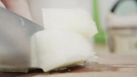 Close up of a knife dicing a white vegetable into cubes on a wooden board Stock Footage 340406723