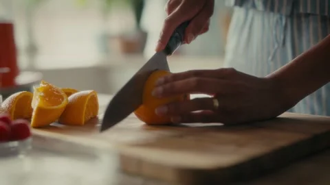Close of a knife slicing and an orange in a kitchen. Stock Footage 312444832