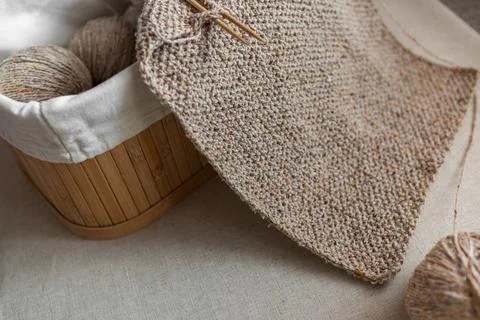 Close-up of knitted texture. Handmade wool scarf of sand color and basket with Фото