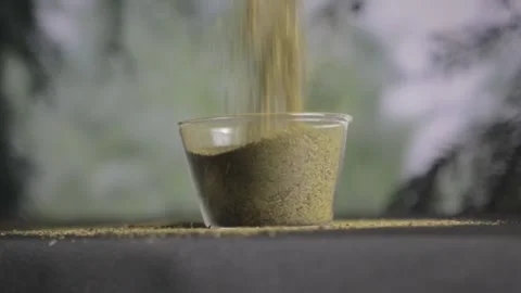 Close up Kratom powder is poured into a glass container Stock Footage