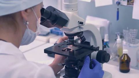 Close up. Lab technician looking through a microscope,close-up shot Stock Footage 99835096