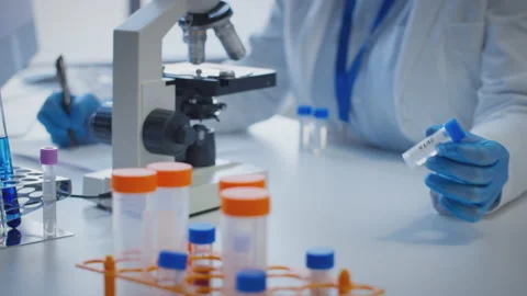 Close Up Of Lab Worker Conducting Research Using Microscope Holding Test Tube La Stock Footage 169886381